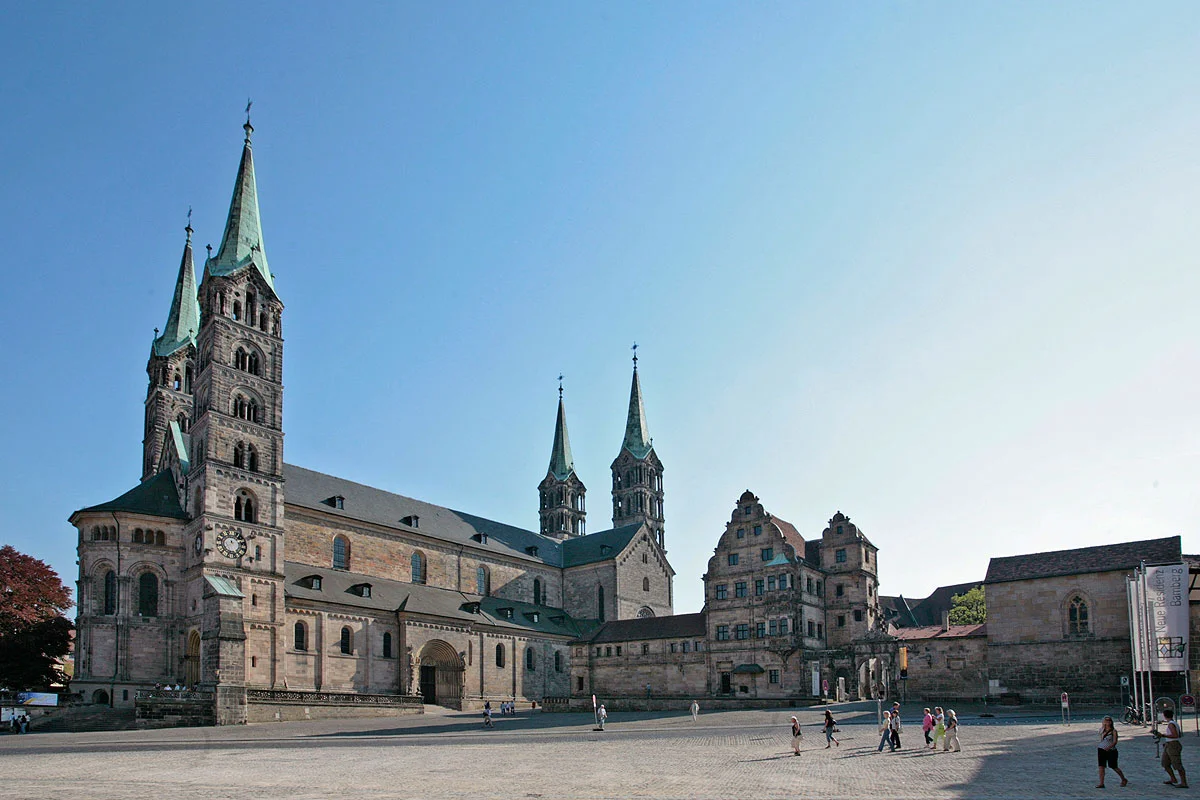 Der viertürmige Kaiserdom auf einem der sieben Hügel Bambergs ist das Herzstück der Stadt und das bedeutendste Kunstwerk im weiten Umkreis. Der Kaiserdom St. Peter und Georg geht auf eine Stiftung von Kaiser Heinrich II. zurück, der 1007 das Bistum Bamberg gründete. Zu den größten Sehenswürdigkeiten zählen das Papstgrab von Clemens II., die einzige vom Vatikan anerkannte Grablege eines Papstes nördlich der Alpen, und der Bamberger Reiter. Trotz zahlreicher Nachforschungen ist seine Identität bis heute nicht geklärt, noch viel weniger die des Künstlers.
Die Alte Hofhaltung, deren Kern die einstige Kaiser- und Bischofspfalz bildet, war früher direkt mit dem Dom verbunden. Durch die "Schöne Pforte" gelangt man in den von Fachwerkbauten umgebenen, romantischen Innenhof. Gleich gegenüber befindet sich der Rosengarten.