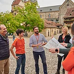 Eine Stadtführungsgruppe  steht in der Alten Hofhaltung. Im hinergrund sieht man den Dom.