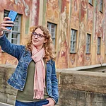 Eine Frau macht ein Selfie auf der Brücke vor dem Alten Rathaus in Bamberg.