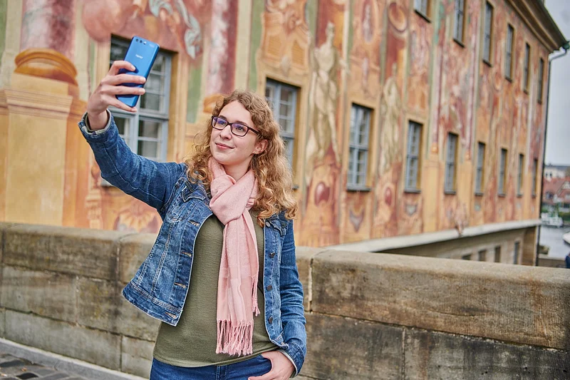 Stadtführung Selfie Eine Frau macht ein Selfie auf der Brücke vor dem Alten Rathaus in Bamberg.