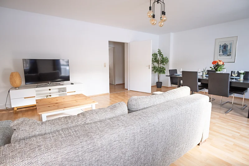 Helles Wohnzimmer der Ferienwohnung in Bamberg für bis zu 6 Personen mit großem Essbereich und direktem Zugang zum Balkon. Ideal für Familien und Gruppen nahe der Bamberger Altstadt.