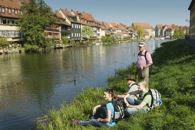 Wanderer machen Rast auf einer Wiese mit Blick auf Klein Venedig.