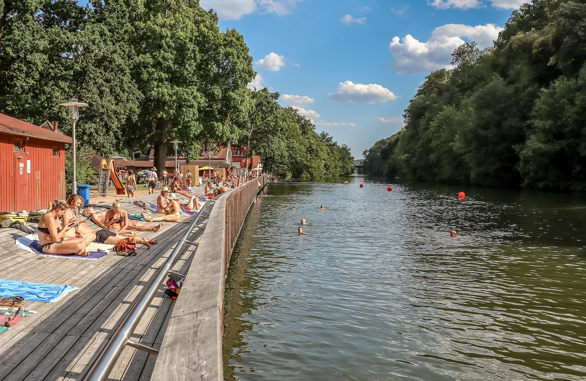 Ein Steg aus Holzbrettern entlang der Regnitz laden im Sommer an der Hainbadestelle zum Sonnenbaden ein.